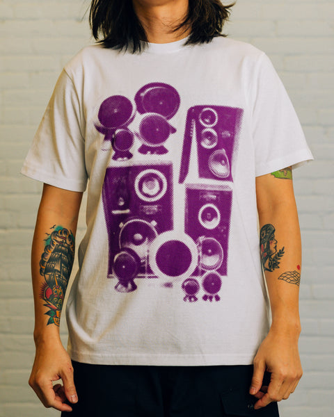Front of white tee with speakers screen printed in purple. The back has “RAISED BY WOLVES CHAMPION SOUND DESIGN” printed.