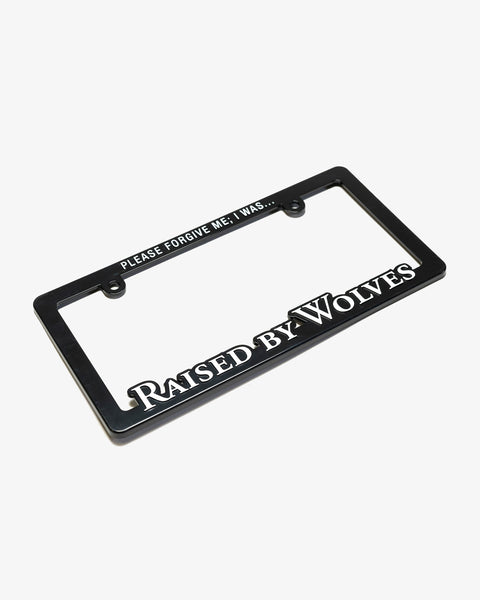Black license plate frame, with the top reading “PLEASE FORGIVE ME; I WAS…” and the bottom reads “Raised By Wolves”.