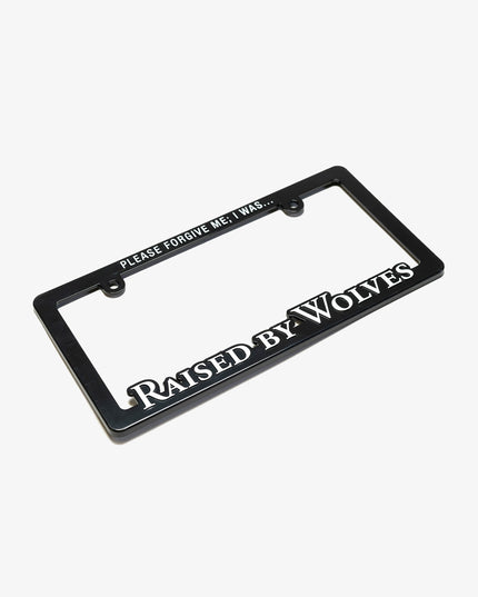 Black license plate frame, with the top reading “PLEASE FORGIVE ME; I WAS…” and the bottom reads “Raised By Wolves”.